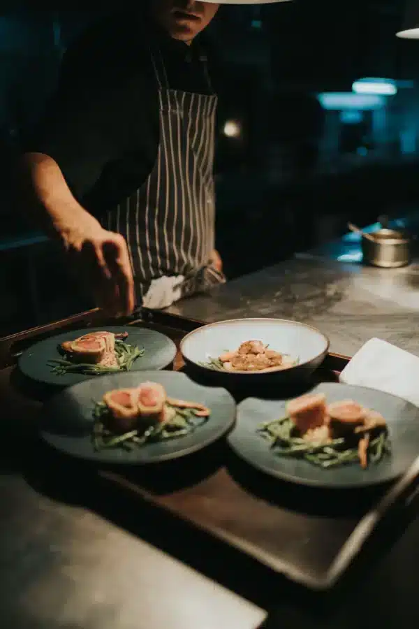Les chefs dressent des plats gastronomiques au restaurant Cuisine du Cloître, mettant en valeur des ingrédients frais et une présentation élégante.