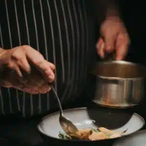 Le chef Guy Queroix réalise le dressage de plats raffinés au restaurant Cuisine du Cloître, avec des ingrédients de haute qualité.