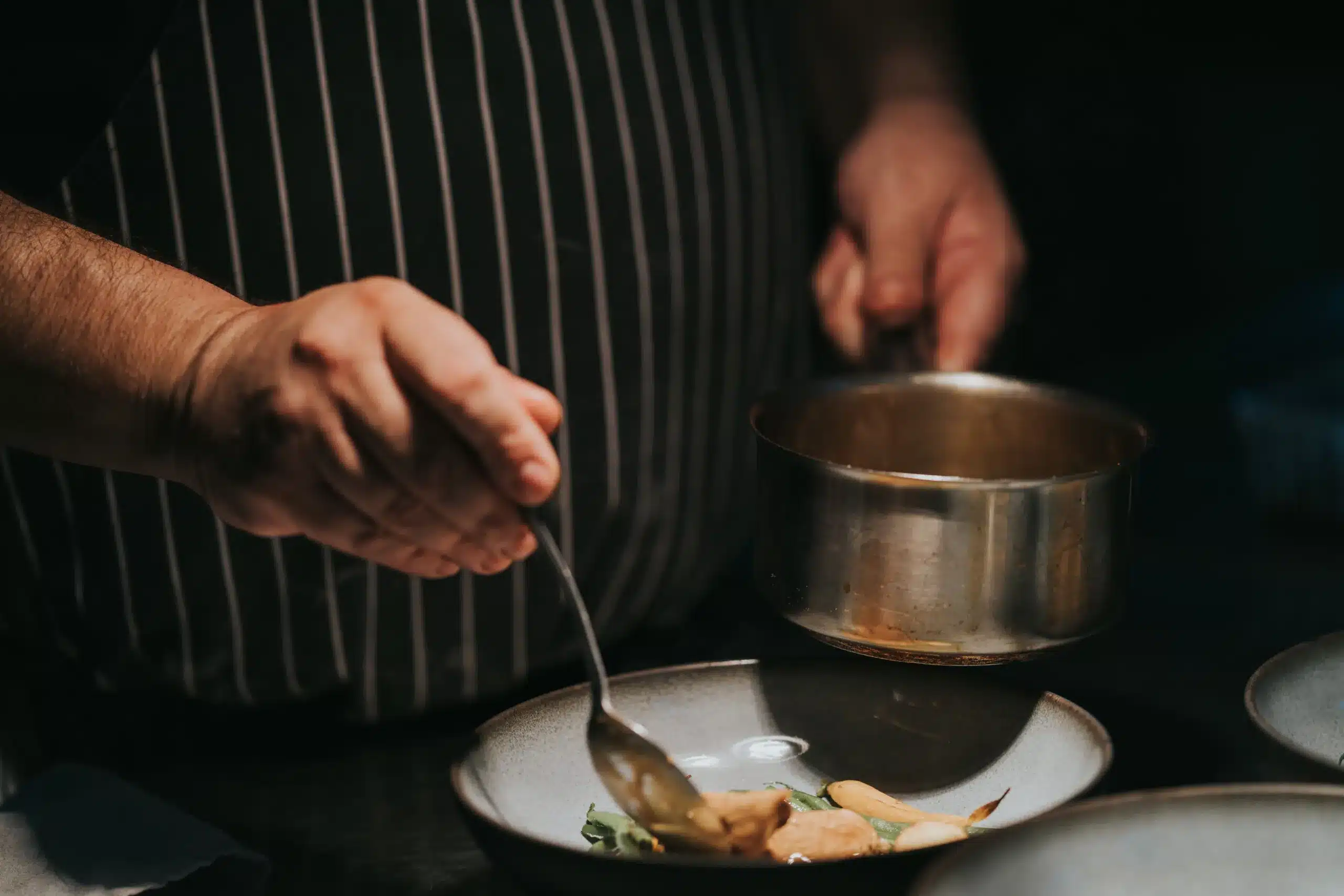 Le chef Guy Queroix réalise le dressage de plats raffinés au restaurant Cuisine du Cloître, avec des ingrédients de haute qualité.